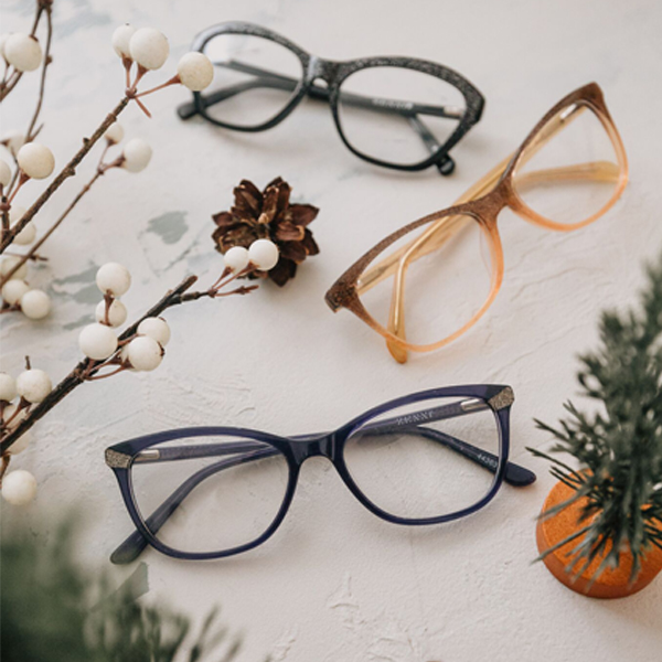 Three pairs of eyeglasses: grey, amber, and purple. The purple frames have "Feminine" on the temple.