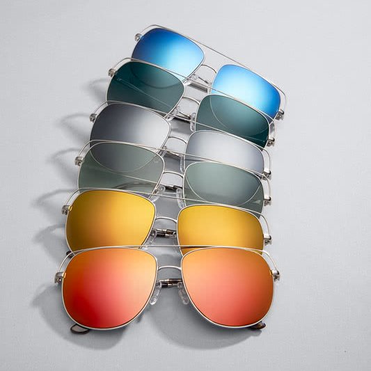 Various styles of aviator sunglasses with different colored lenses: blue, gray, green, yellow, and orange.