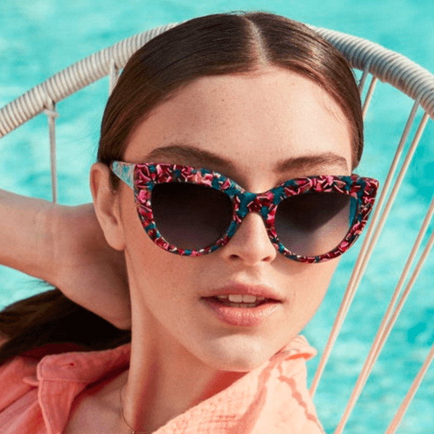 Woman wearing floral-patterned cat-eye sunglasses with dark lenses.