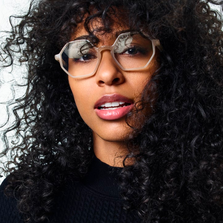 Woman wearing hexagonal, clear frame eyeglasses.