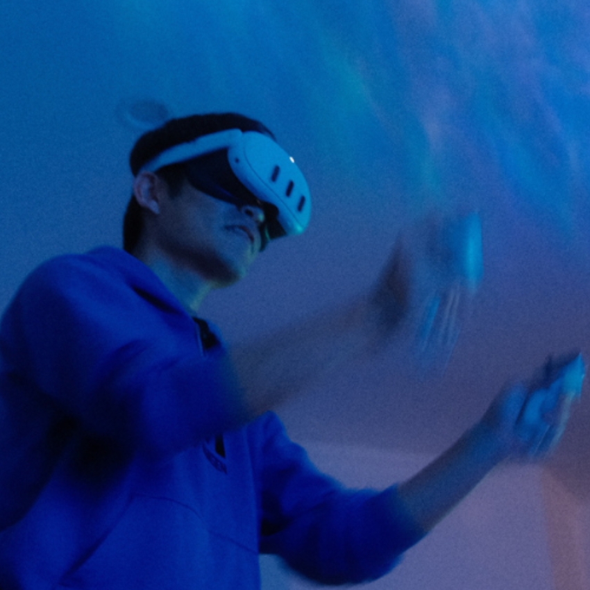 Person wearing a VR headset, engaging in virtual reality experience with handheld controllers.