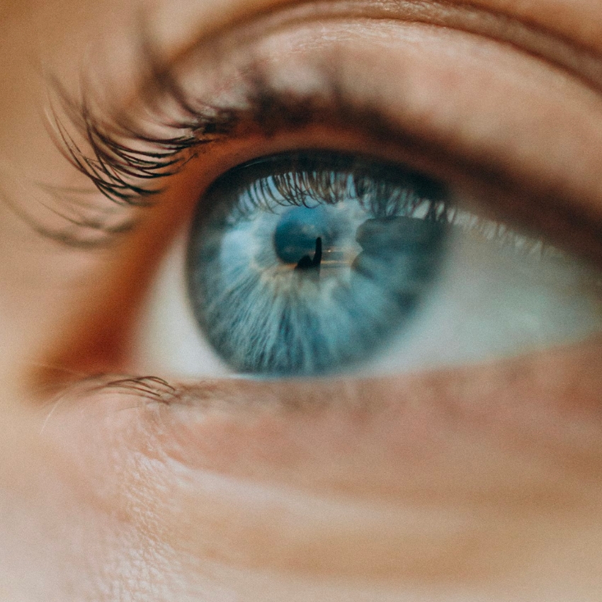 Close-up of a blue eye with visible eyelashes and detailed iris texture.