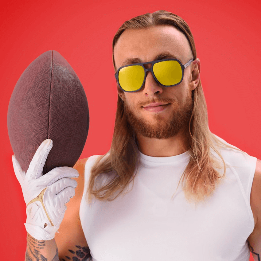Man with sunglasses and a white sleeveless shirt holding a football.