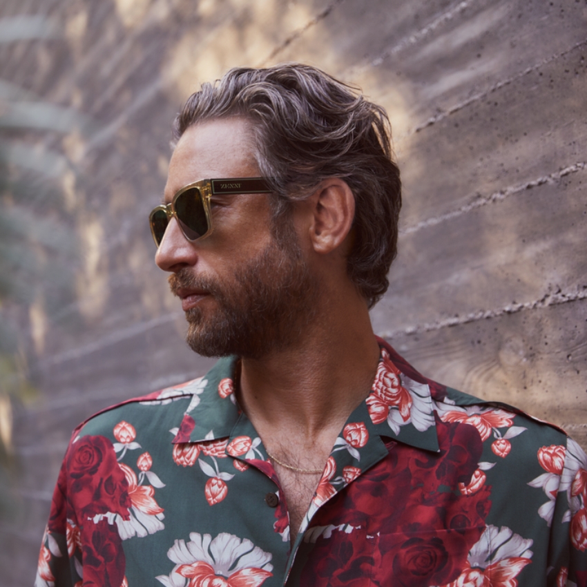 Man wearing VONZOY sunglasses and a floral print shirt with red, white, and green patterns.