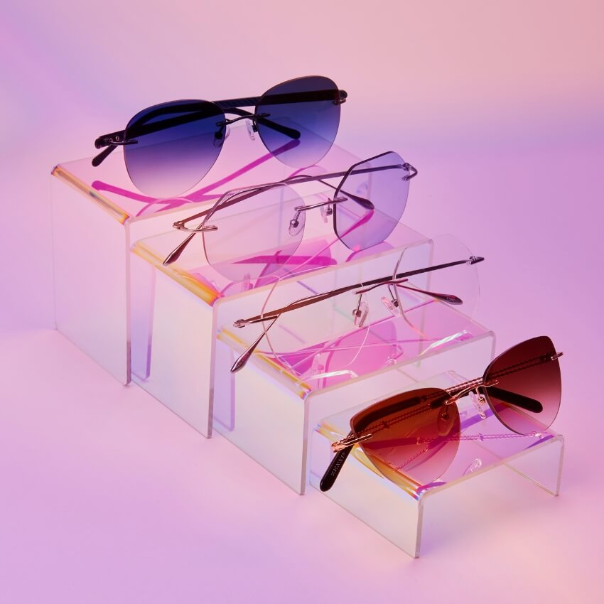 Variety of stylish sunglasses on display stands; includes aviators, oversized, and geometric shapes.