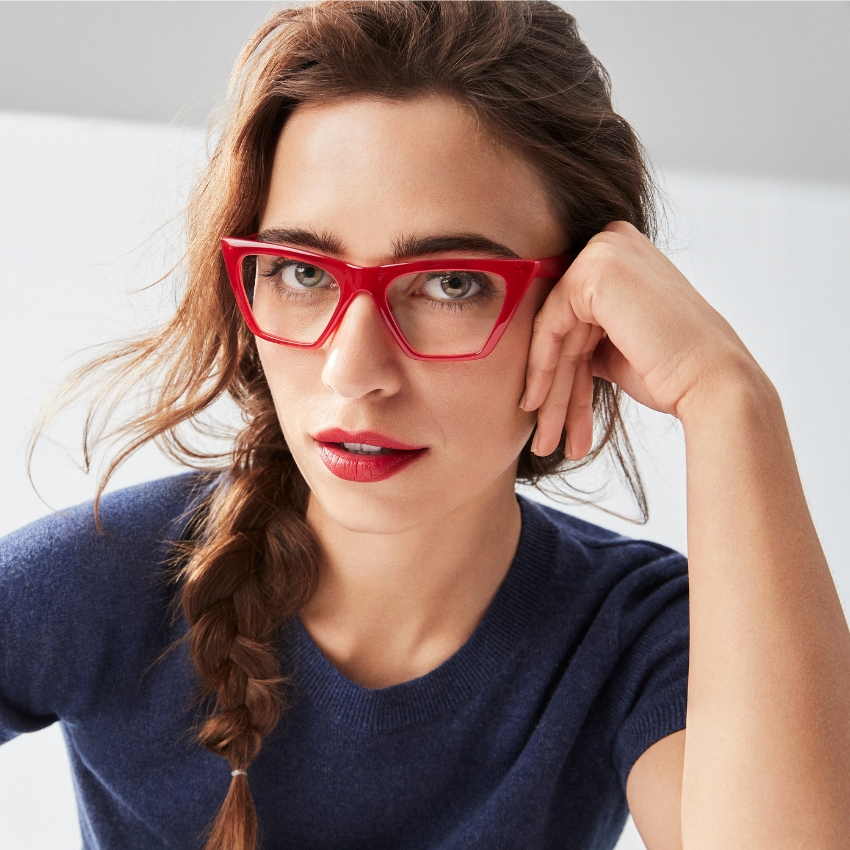 Woman wearing red eyeglasses and a blue sweater.