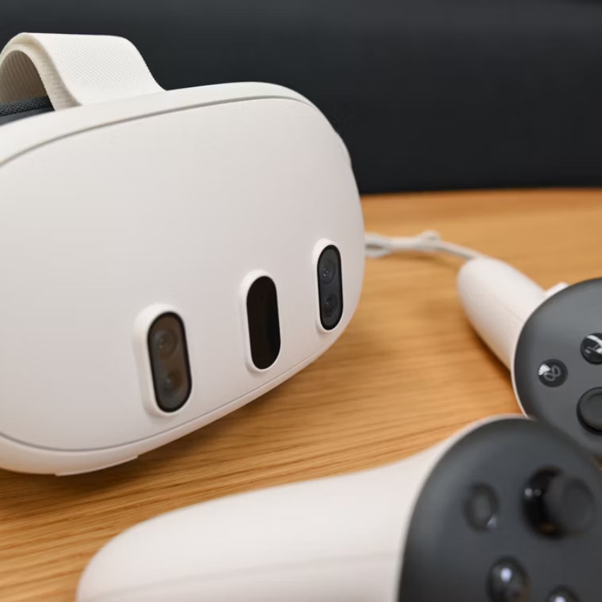 White virtual reality headset with dual controllers on a wooden surface.