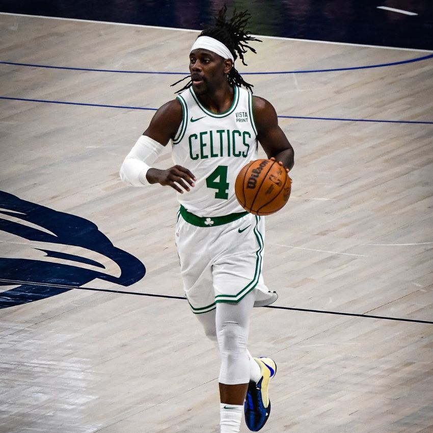 Basketball player wearing a white Celtics jersey with number 4, holding a basketball during a game.