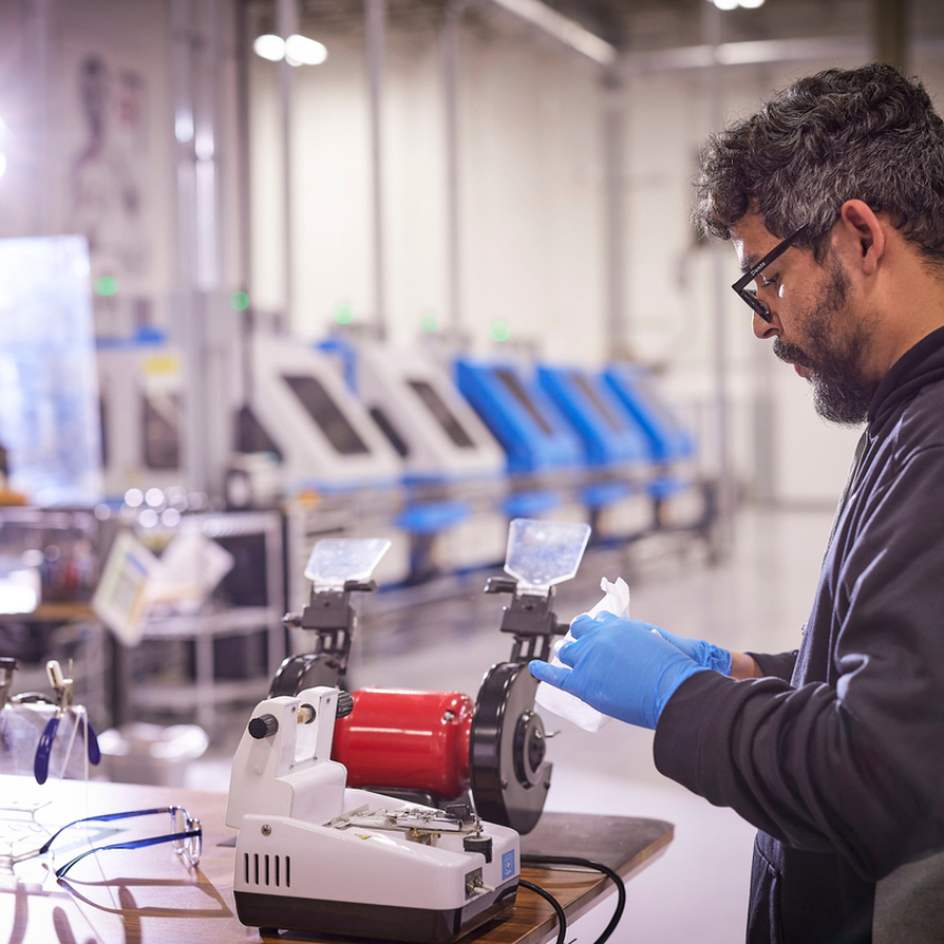 Man wearing blue gloves using industrial equipment.